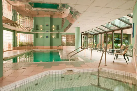 Indoor swimming pool and tiled spa beside a row of windows