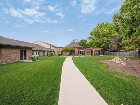 Low residence buildings beside a lawn and straight concrete pathway