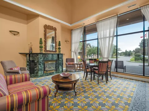 Seating area with striped armchairs, a fireplace and tall windows