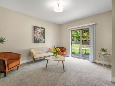 Room with a small sofa, armchair and patio doors opening onto a lawn