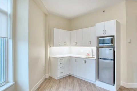 Kitchen with white cabinets, sink, microwave and refrigerator.