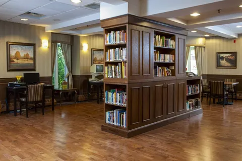 Library with bookcases, tables, chairs and a fireplace.