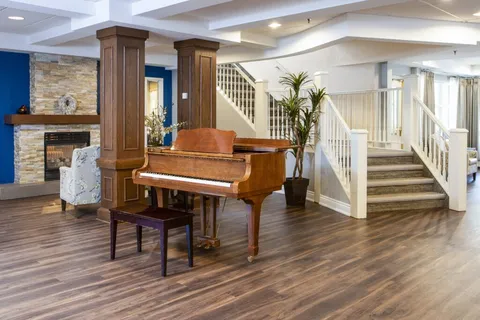 Lobby with a grand piano, fireplace and stairway.