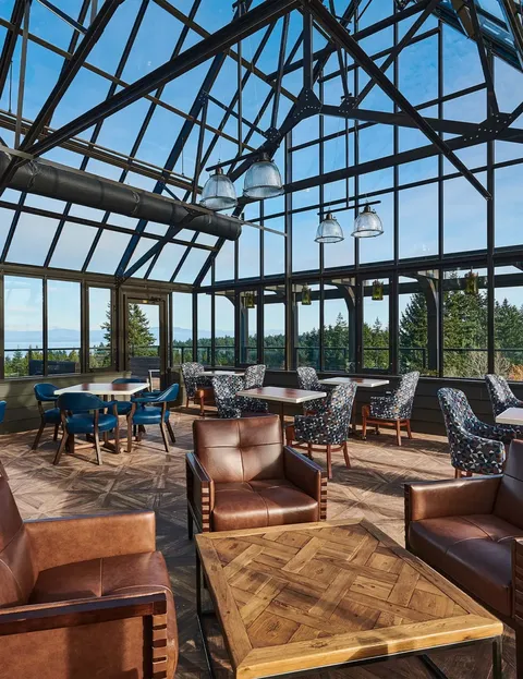 Glass-roofed lounge with leather and patterned chairs, tables and pendant lights.