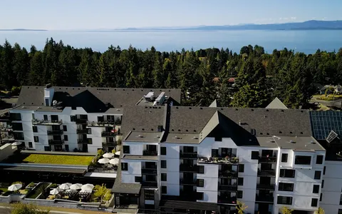 Aerial view of the residence with balconies, roof terraces and trees beside the coastline.