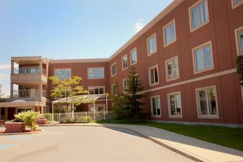 Three-storey residence exterior with balconies, a covered entrance and garden.