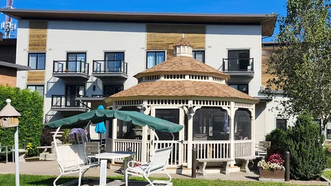 Gazebo with garden chairs and umbrellas beside the residence