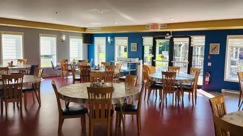 Dining room with round tables, wooden chairs and glass doors