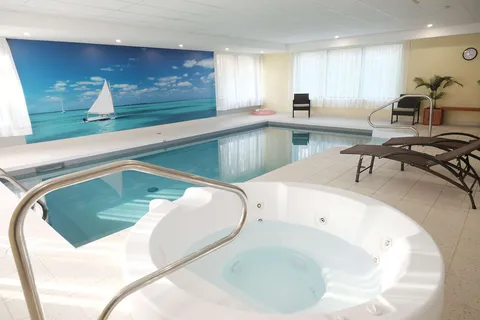 Indoor swimming pool and spa beside large windows.