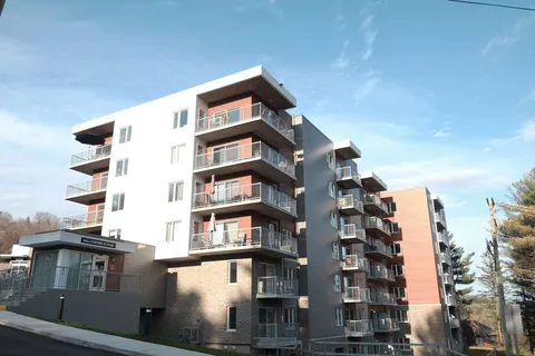Residence building with balconies seen beside trees.