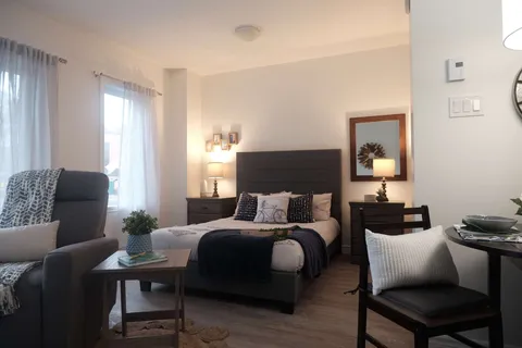 Studio room with an adjustable bed, chairs and a dining table.