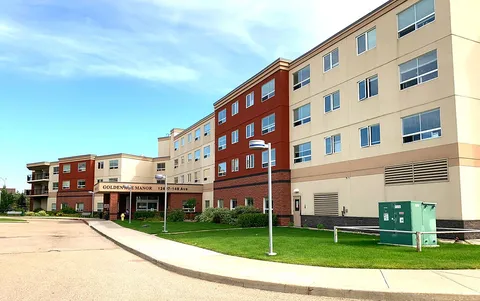 Residence exterior with a paved driveway, lawn and multi-storey wings.