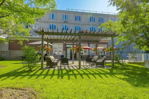Lawn and outdoor seating beneath a pergola beside the residence