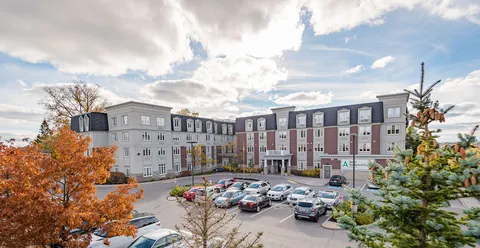 View of a multi-storey residence and parking area among autumn trees
