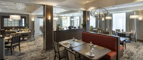 Dining room with set tables, upholstered seating and ceiling lights.