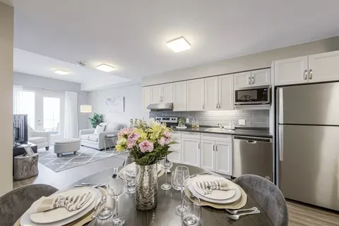 Suite kitchen with white cupboards and a round dining table.