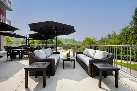 Outdoor terrace with sofas, tables and umbrellas beside a railing.