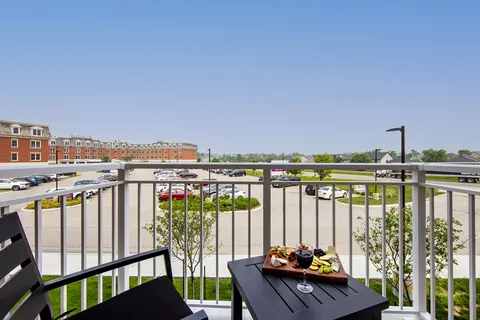 Suite balcony with a table, chairs and a view of the residence grounds.