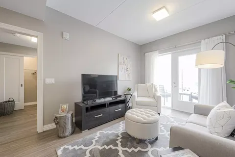 Suite living area with a television, armchair and doors to a balcony.