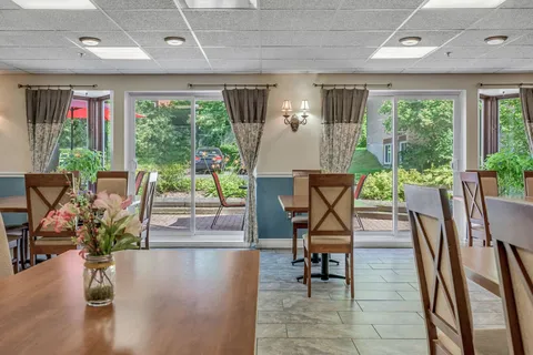 Room with dining tables, wooden chairs and large windows