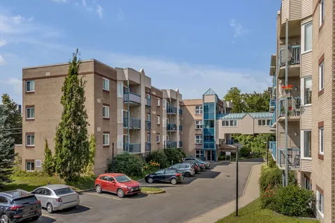Residence buildings beside a paved entrance drive and parked cars