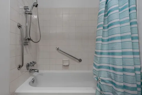 Bathroom with a bathtub, shower curtain and grab rails