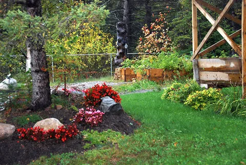 Flower beds and lawn beside trees and a timber gazebo
