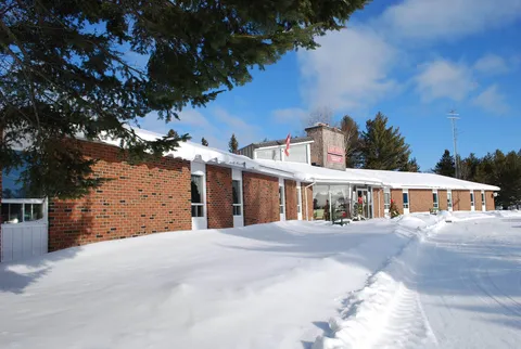 Single-storey brick building beside snow-covered grounds and trees