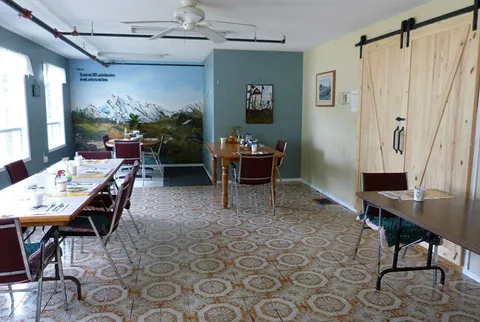 Dining room with tables, chairs and a mountain mural