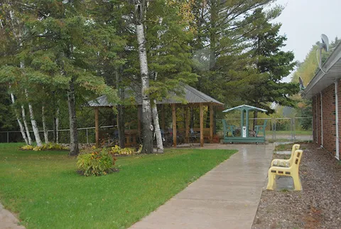 Paved path through a lawn beside a gazebo and trees