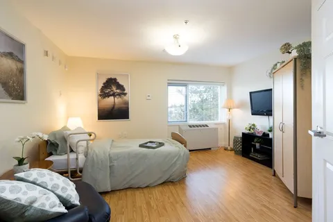 Bedroom with a pale duvet, armchair, wardrobe and dark television