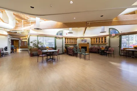 Dining tables, chairs and a fireplace beneath timber ceiling beams