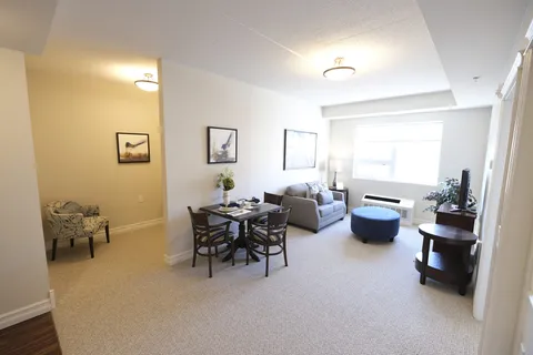 Room with a sofa, a blue ottoman, dining furniture and framed bird pictures