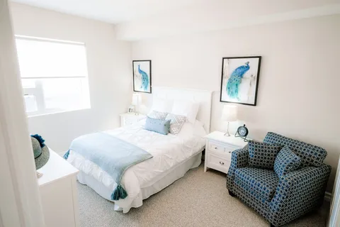 Bedroom with a bed, pale blue bedding and framed bird pictures