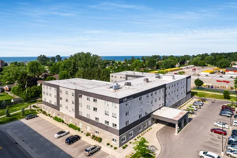 Aerial view of a multi-storey grey residence, parking areas and surrounding roads