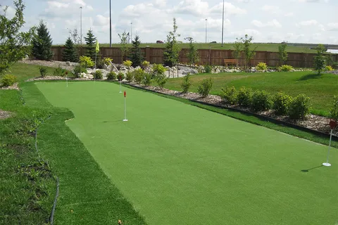 Outdoor putting green surrounded by landscaped beds.