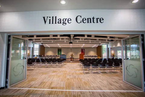 Village Centre hall with rows of chairs and wooden flooring.