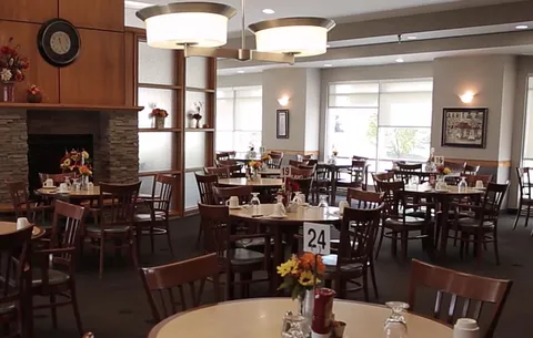 Dining room with wooden tables, chairs and ceiling lights.