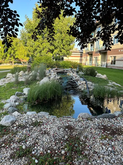 Garden pond with a fountain surrounded by planting beds.