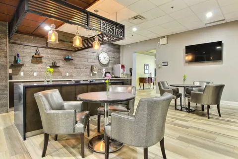 Bistro counter with hanging lights beside round tables and upholstered chairs