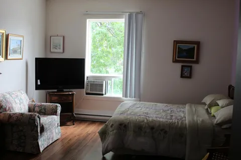 Bedroom with a bed, armchair, television and window air conditioner.