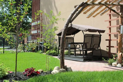 Garden with a lawn, flower beds, pergola and covered swing.
