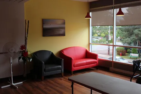 Window seating area with a red sofa, black chairs and a coffee table.