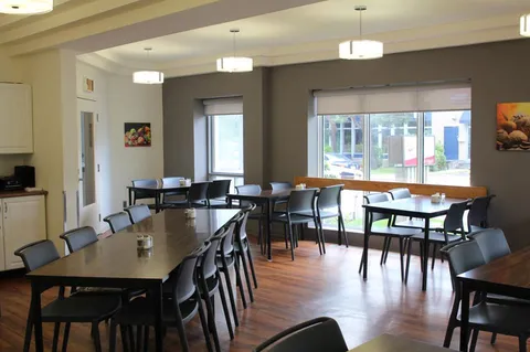 Dining room with wooden tables, black chairs and windows.