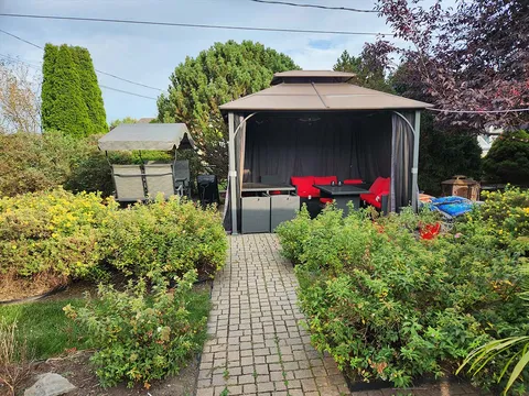 Garden path leading to a gazebo with red chairs among flowers