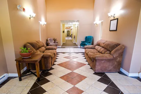 Sitting area with brown sofas, armchairs and a patterned tile floor