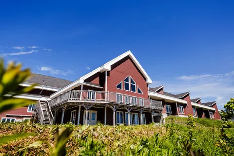 Red residence with gabled roofs, a raised deck and planting beds