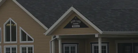 Front of a building with a gabled roof and a Deer Lake Manor sign
