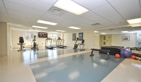 Fitness room with exercise machines, benches, mats and large windows