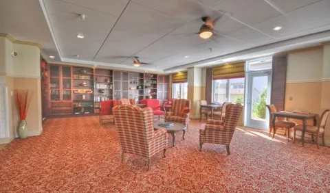 Room with plaid armchairs, bookcases, ceiling fans and large windows